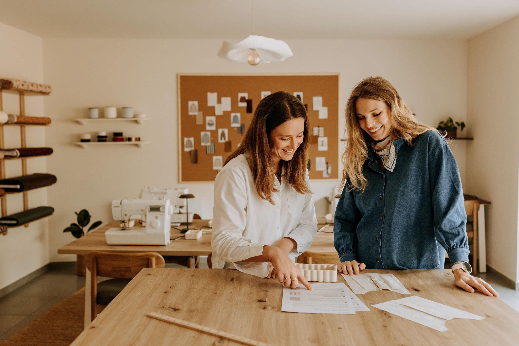 Deux femmes étudiant un patron sur la table de l'atelier, devant le tableau de croquis