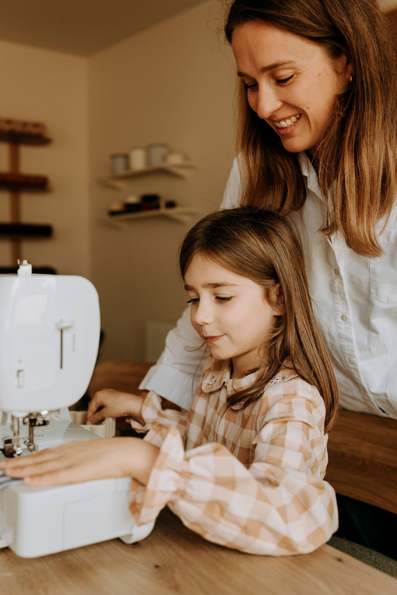 Une enfant et une femme cousant ensemble à la machine dans l'atelier
