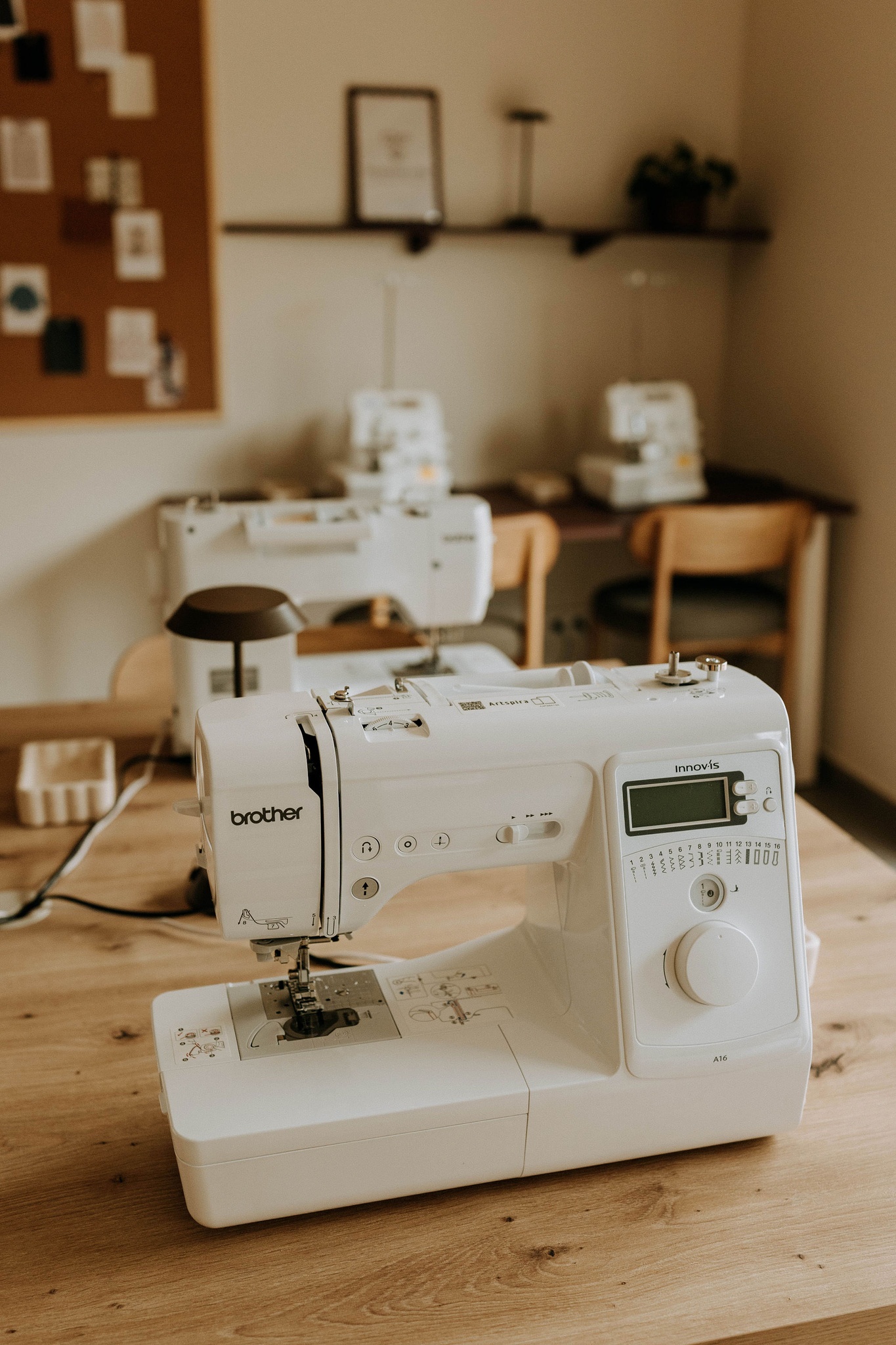 Machine à coudre Brother posée sur la table de l'atelier, devant les postes de couture