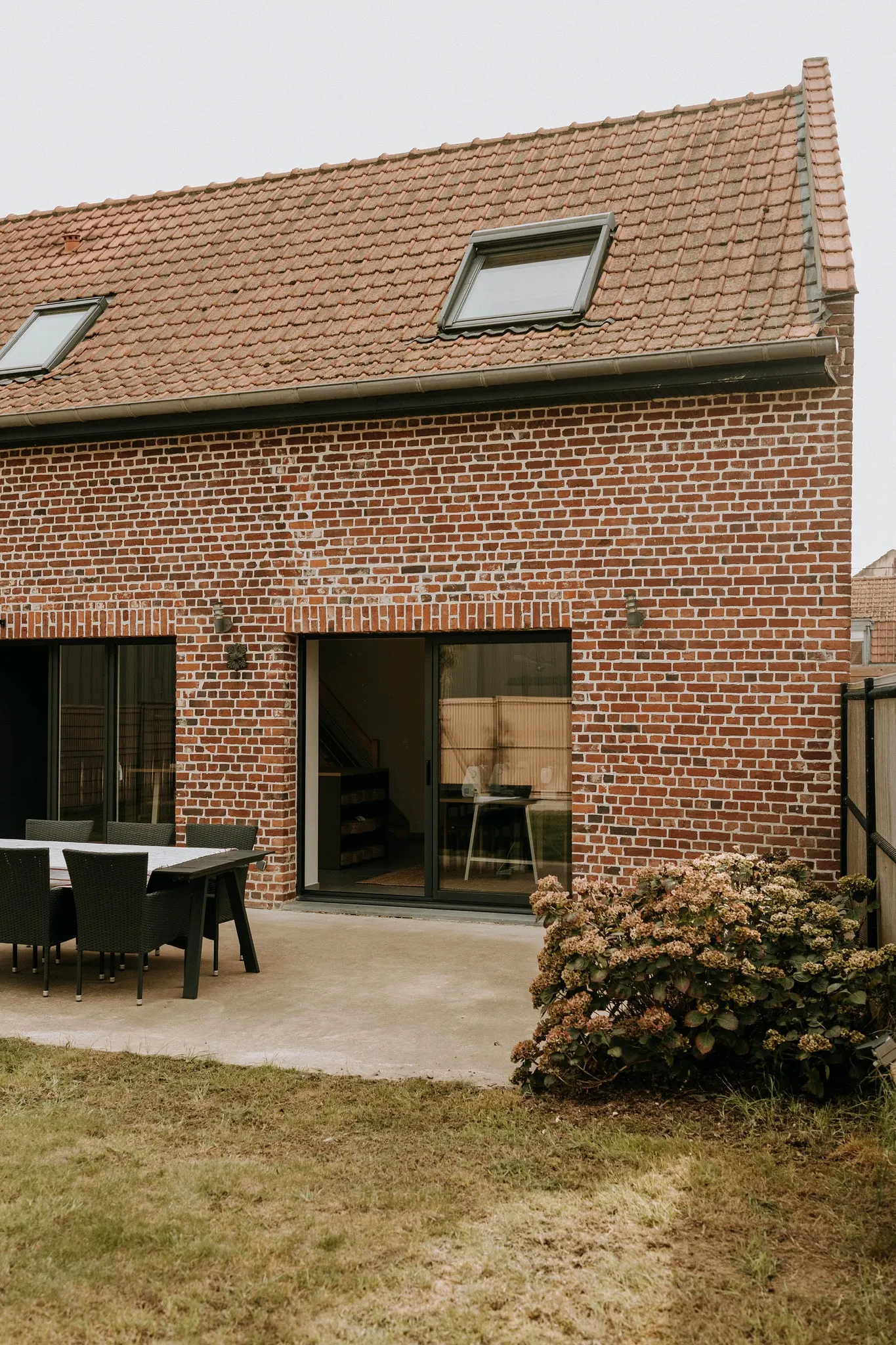 La cour arriere de l'atelier : terrasse, grande baie vitree ouverte et jardin