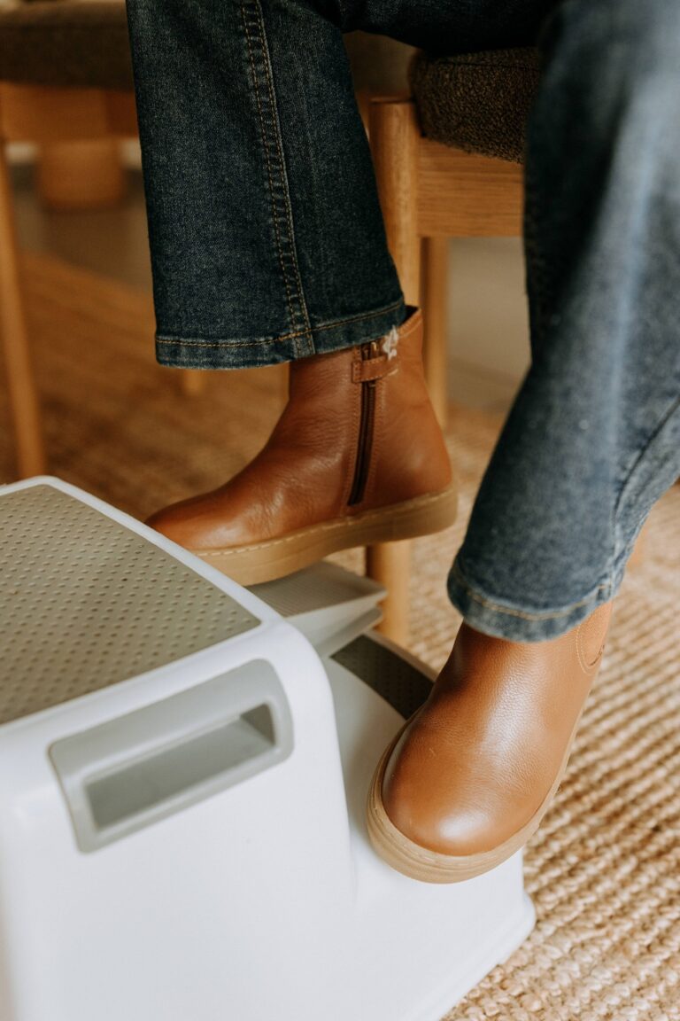 Détail de tenue à l'atelier : bottes de cuir posées sur un marchepied